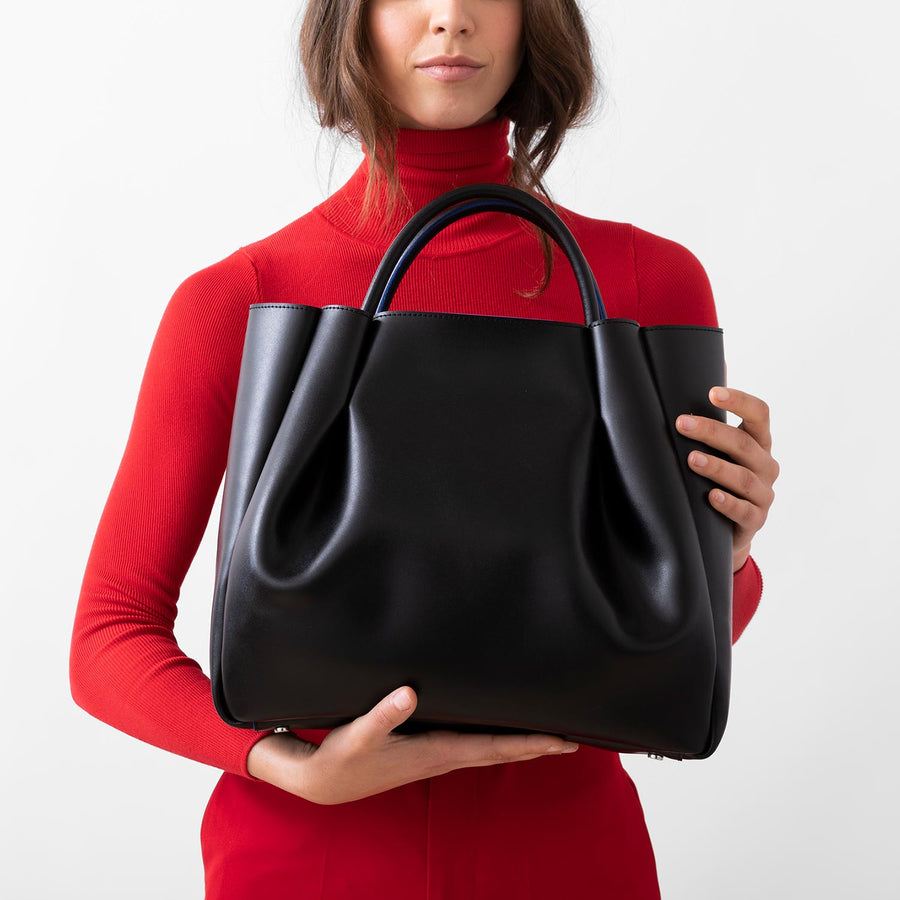 woman holding large black leather tote bag purse