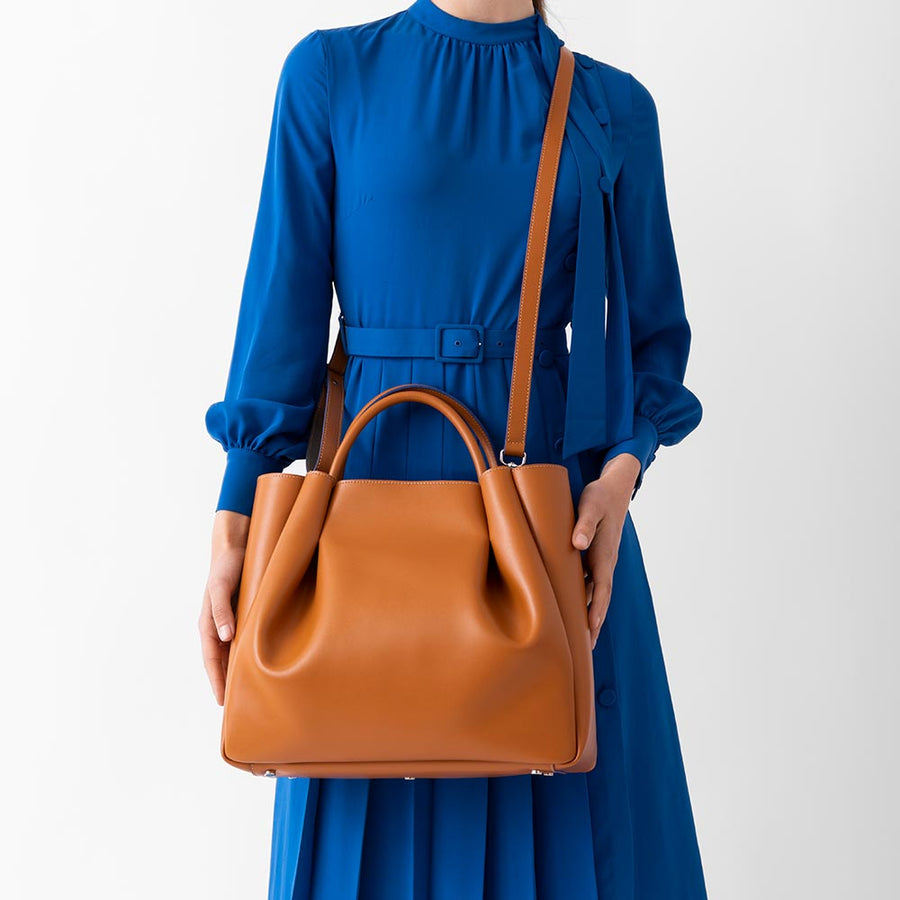 woman wearing large tan cognac leather tote bag purse with shoulder strap