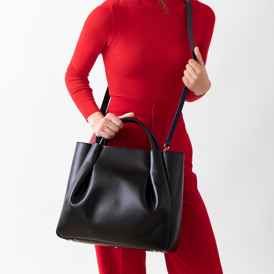 woman holding large black leather tote bag purse with shoulder strap