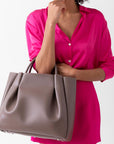 woman with large taupe brown leather tote bag purse