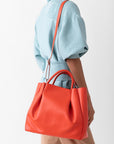 woman with large orange leather tote bag purse with shoulder strap