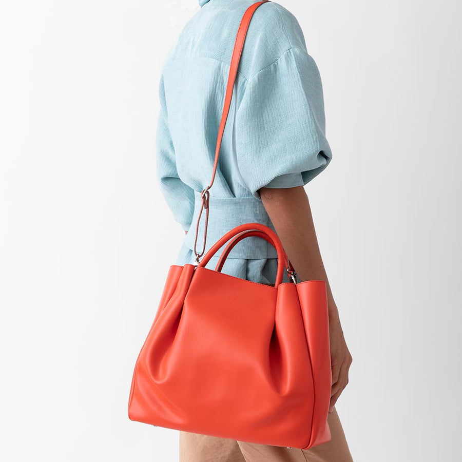 woman with large orange leather tote bag purse with shoulder strap