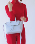 woman wearing medium sky blue leather work tote bag purse with shoulder strap