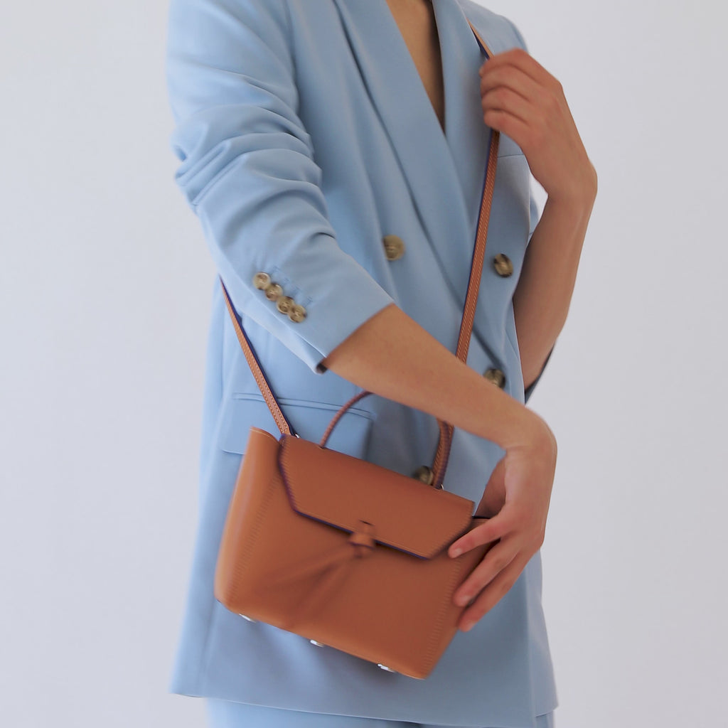 woman wearing mini satchel bag cognac brown leather purse with shoulder strap
